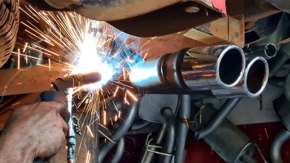 Welder Attaching Dual Exhaust Tips to a Vehicle — Gladstone Mufflers & Suspension In Gladstone Central, QLD