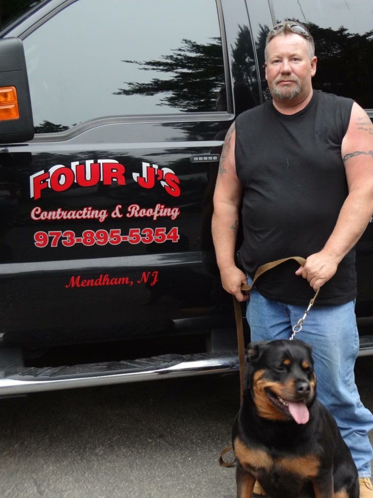 A Man Standing Next to A Dog in Front of A Four J 's Truck.
