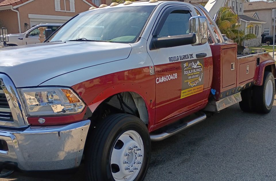 Red and silver utility pickup truck parked on a street with a ladder rack and side tool compartments