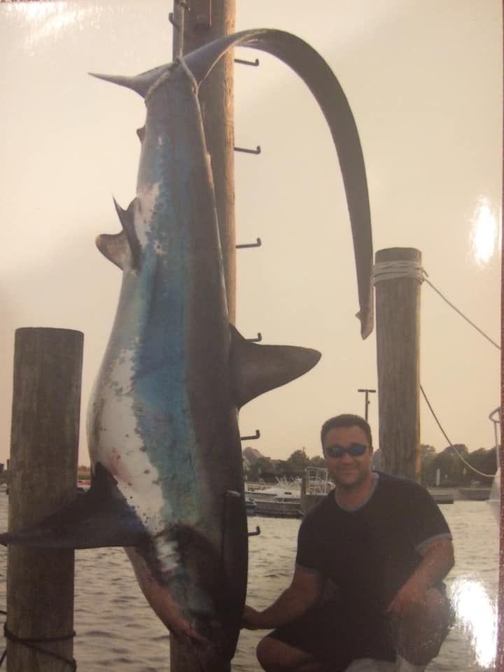 man sitting beside a hanging shark