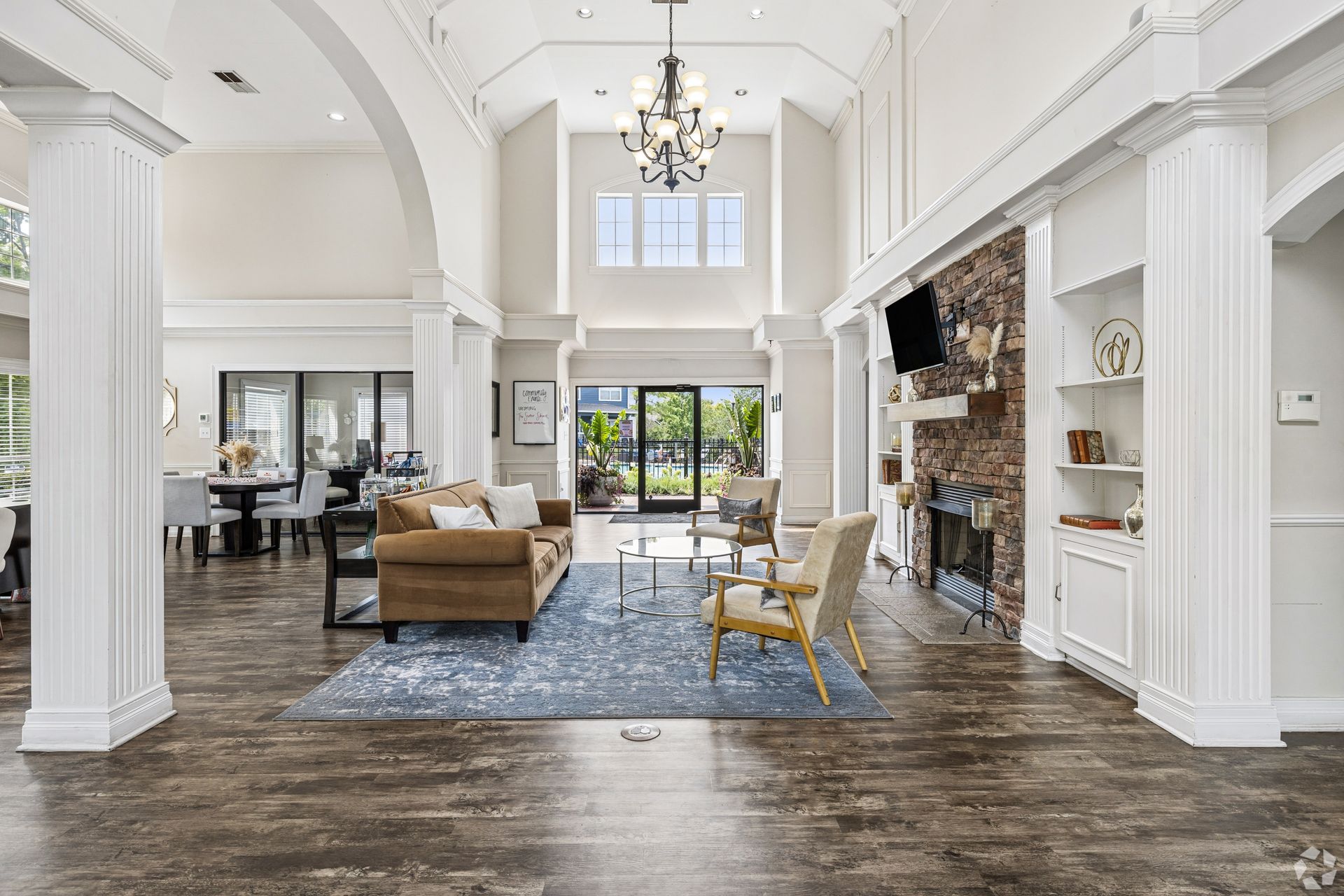 Bright open clubhouse with high ceilings, fireplace, white walls, blue rug, and brown seating