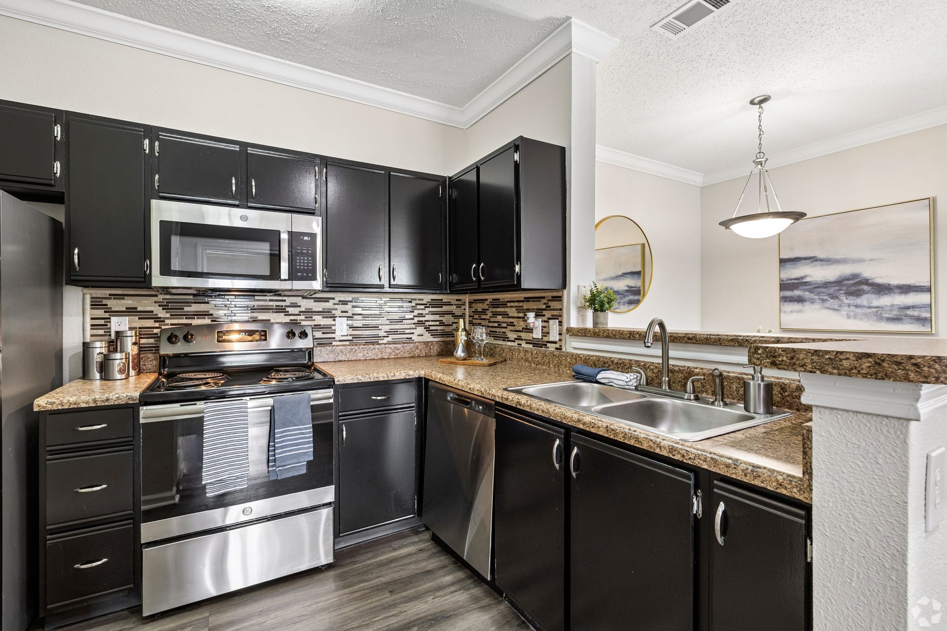 Modern kitchen with dark cabinets, stainless appliances, and granite counters