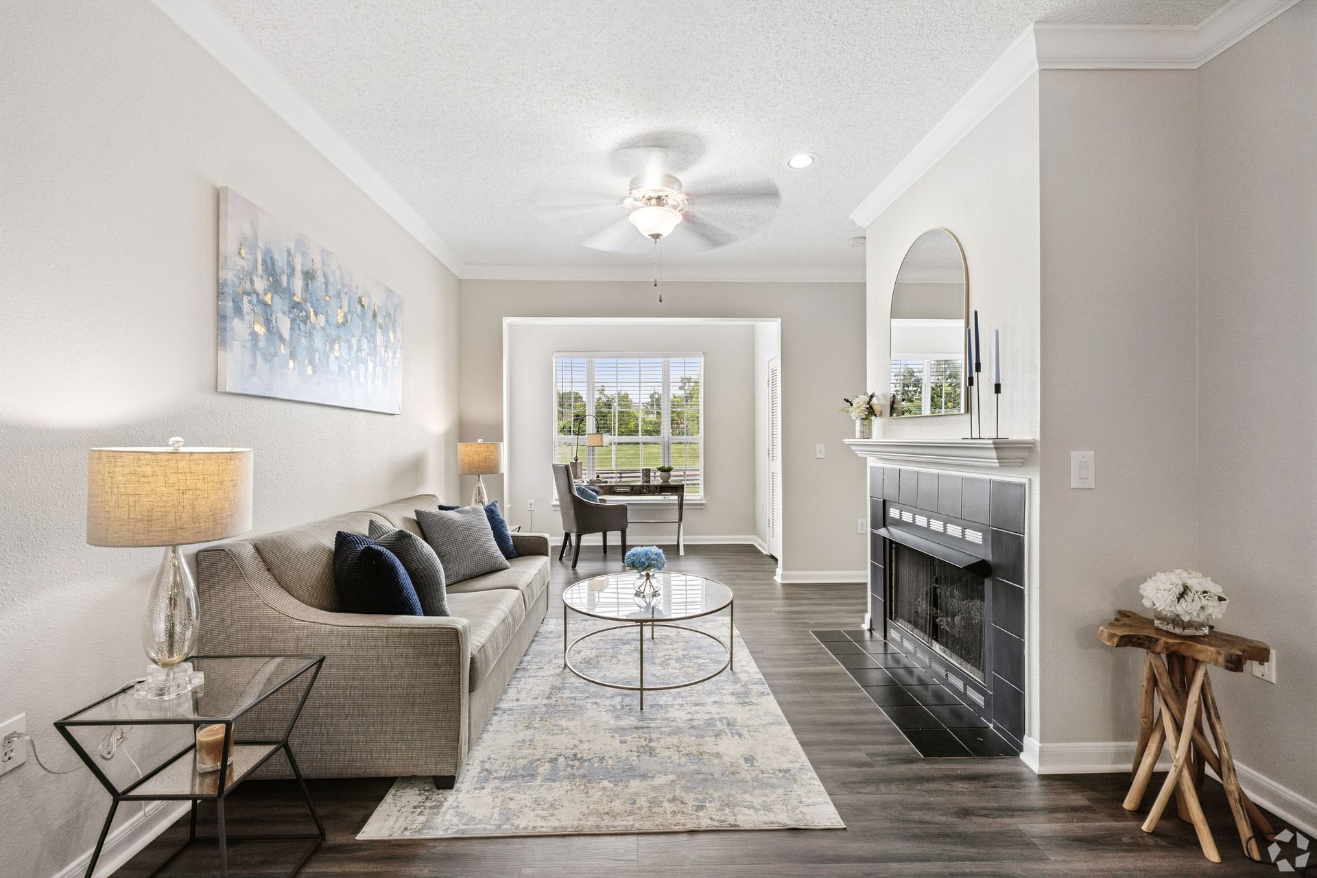 Bright living room with gray sofa, fireplace, coffee table, and dining area beyond large windows