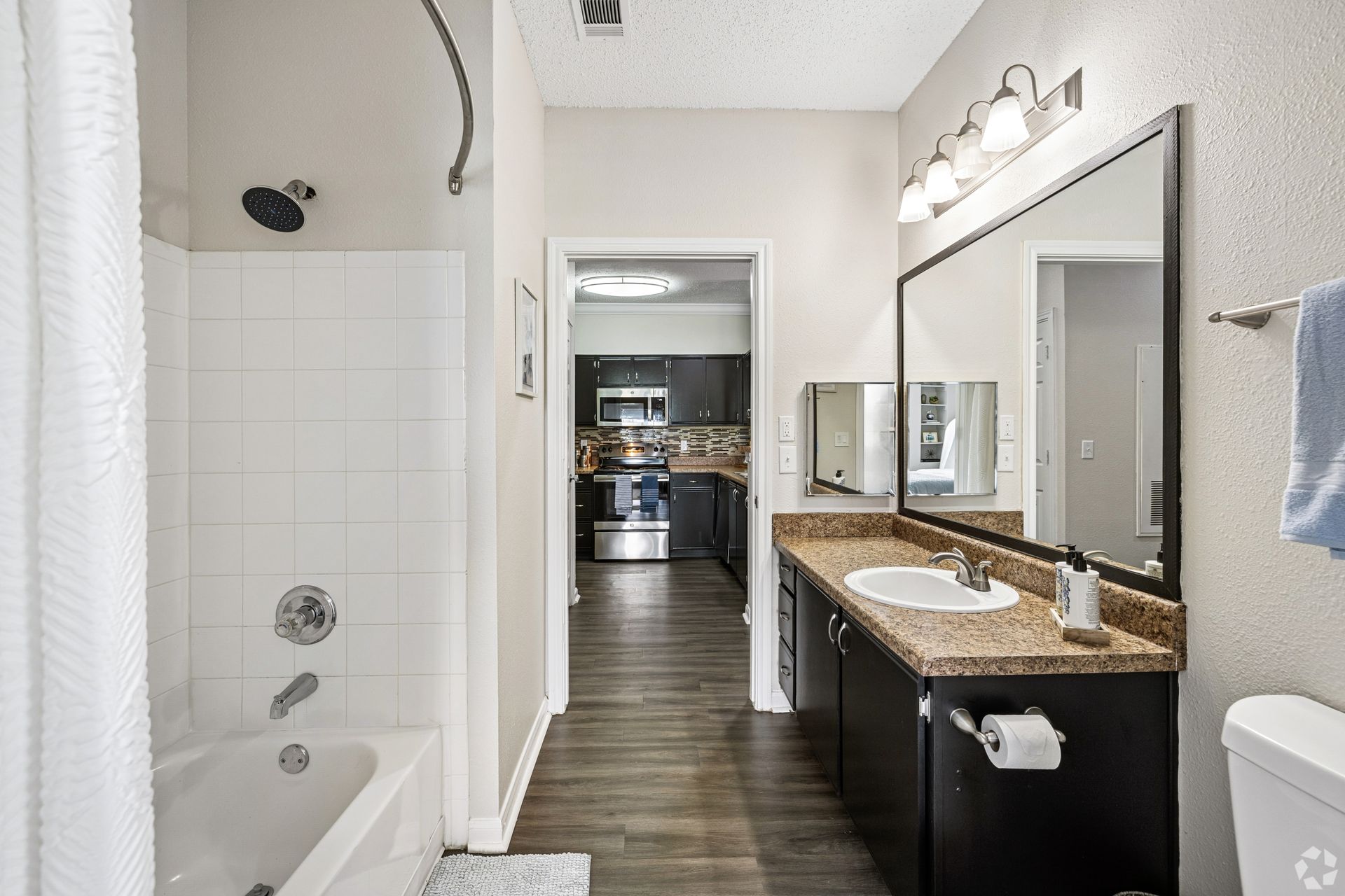 Bathroom with shower/tub, vanity, and mirror off of the kitchen area.