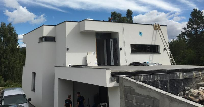 Moderne hvitt toetasjes hus med balkong, takstige og folk samlet under carporten
