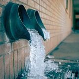 Water pouring from two wall drains into a pool, with ice buildup along the edge.