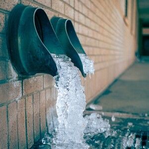 Water pouring from two wall drains into a pool, with ice buildup along the edge.