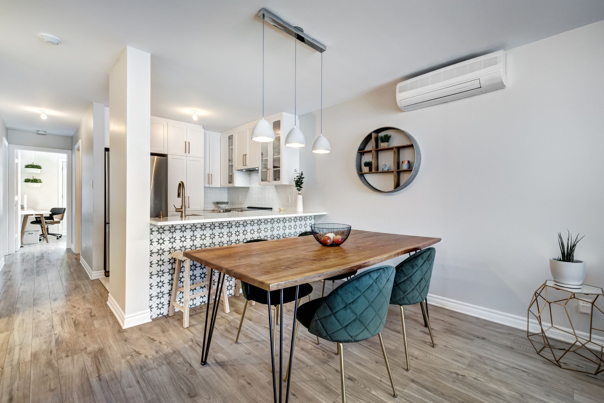 a dining room with a wooden table and chairs and a kitchen in the background .