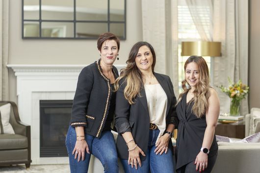 Three women are posing for a picture in a living room.