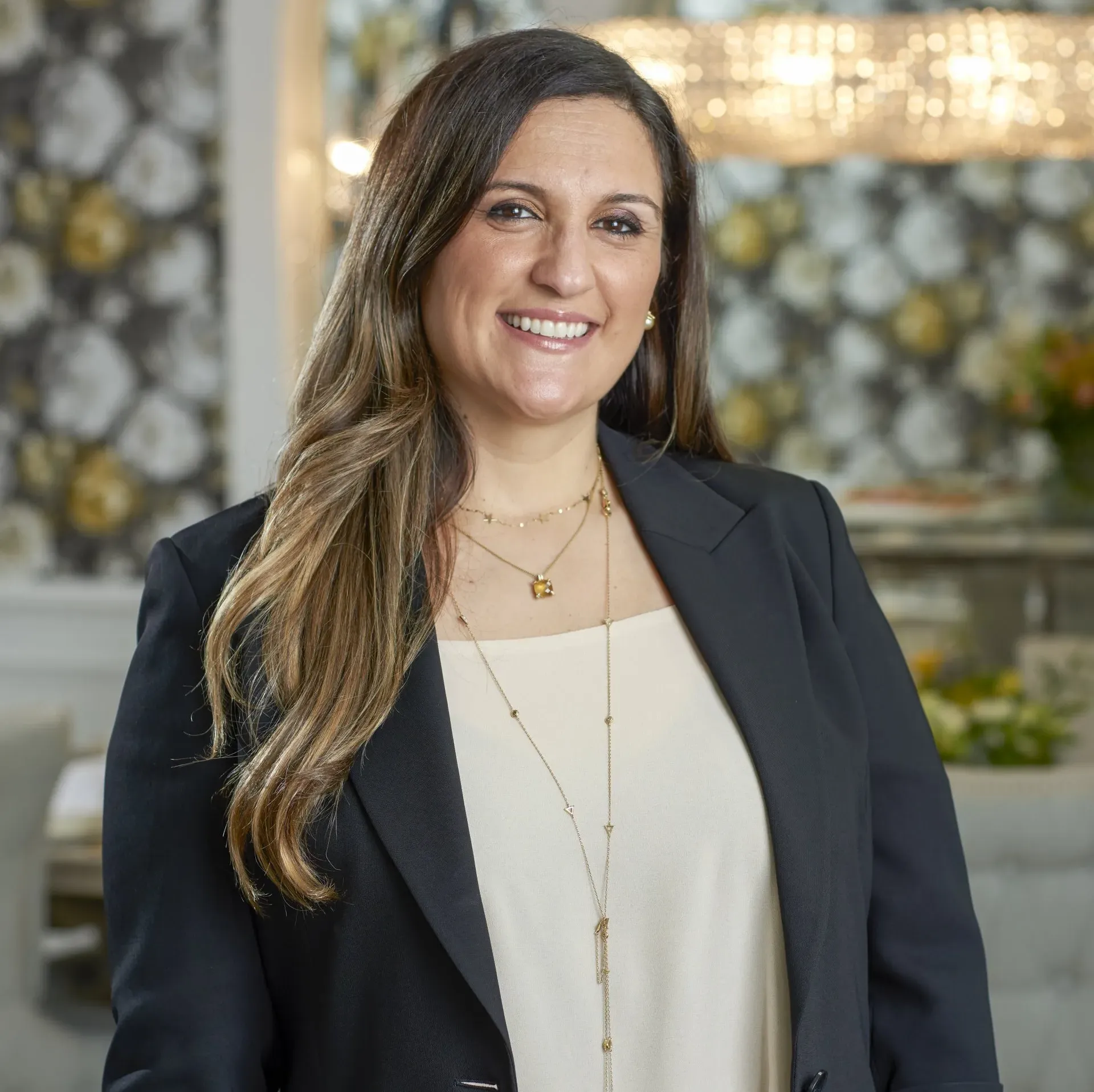 A woman in a black jacket and white shirt is smiling for the camera.