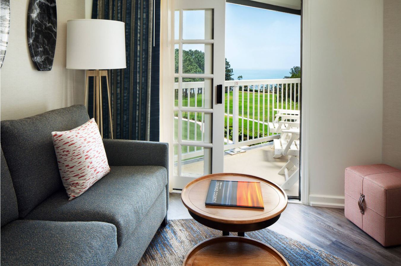 A living room with a couch , table , lamp and balcony.