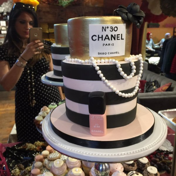 A woman taking a picture of a chanel cake