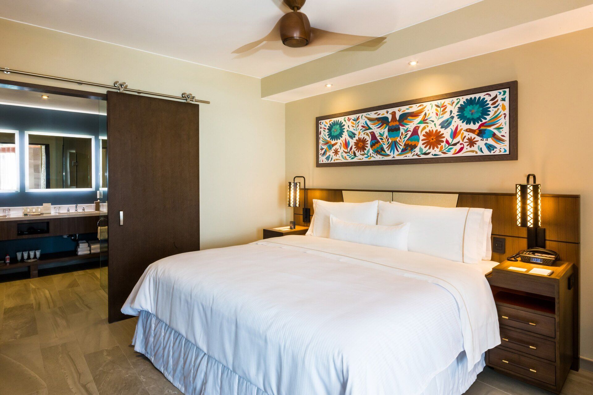 A hotel room with a king size bed and a ceiling fan.