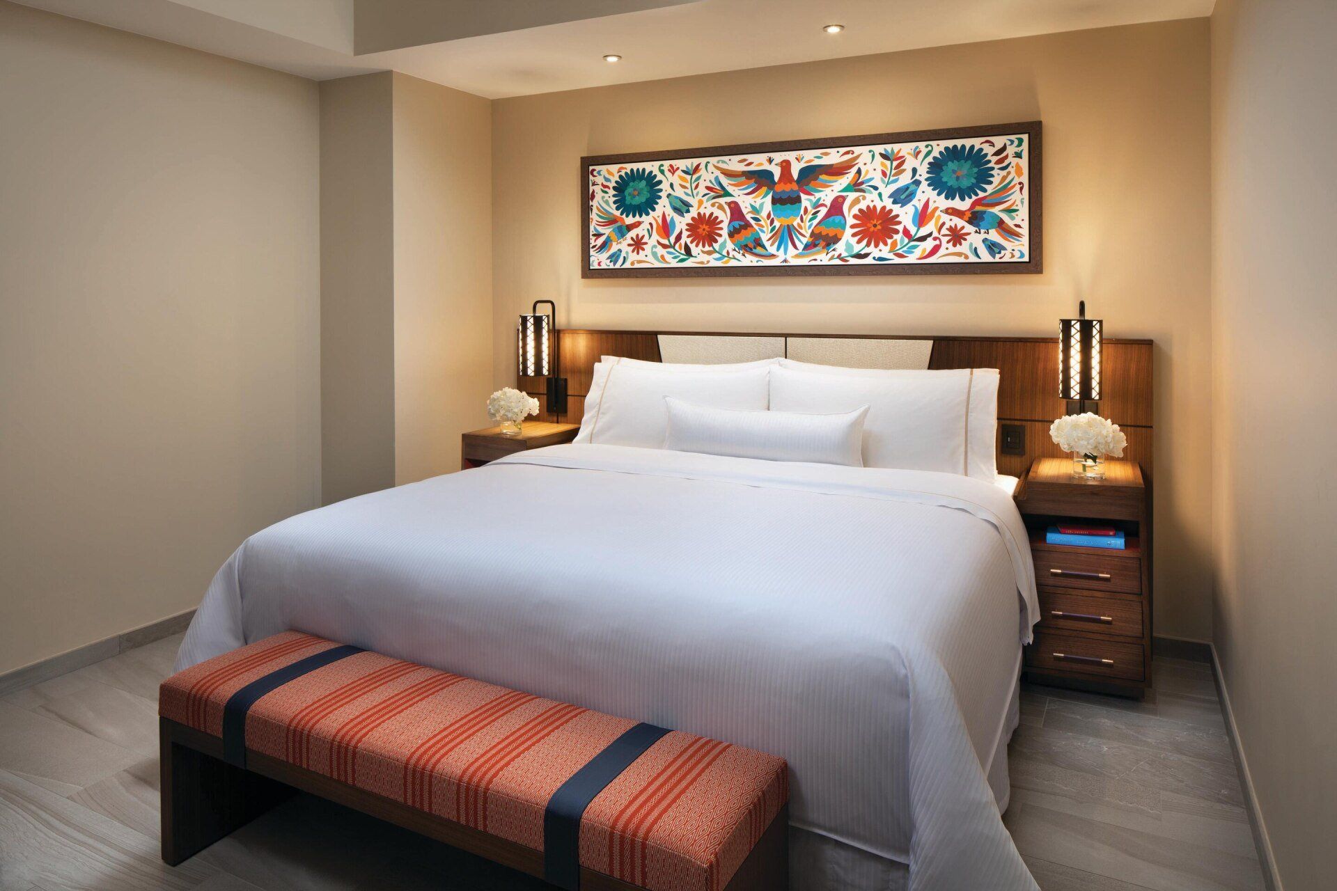 A hotel room with a large bed and a bench