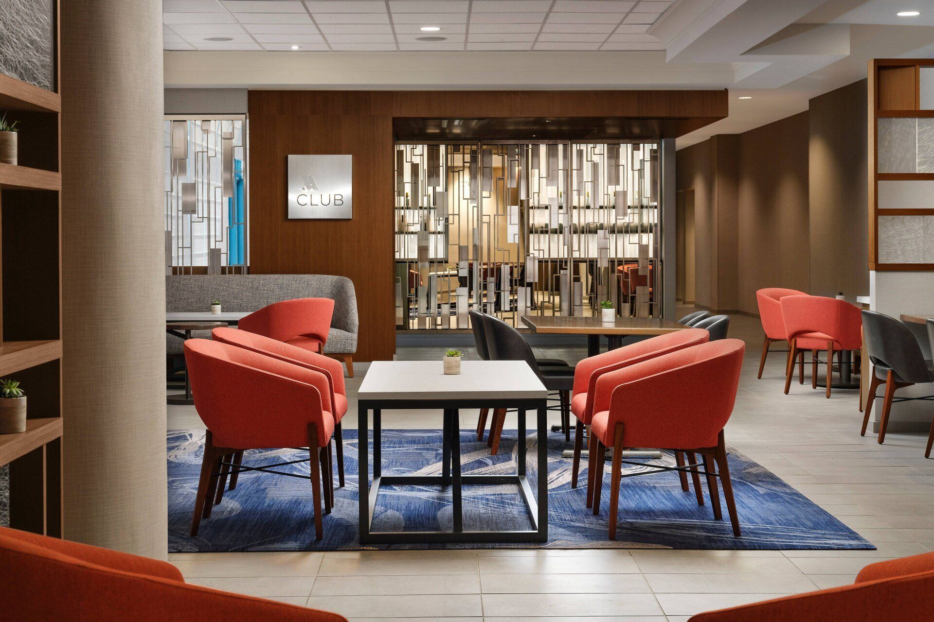 A living room with red chairs , tables , and a couch.