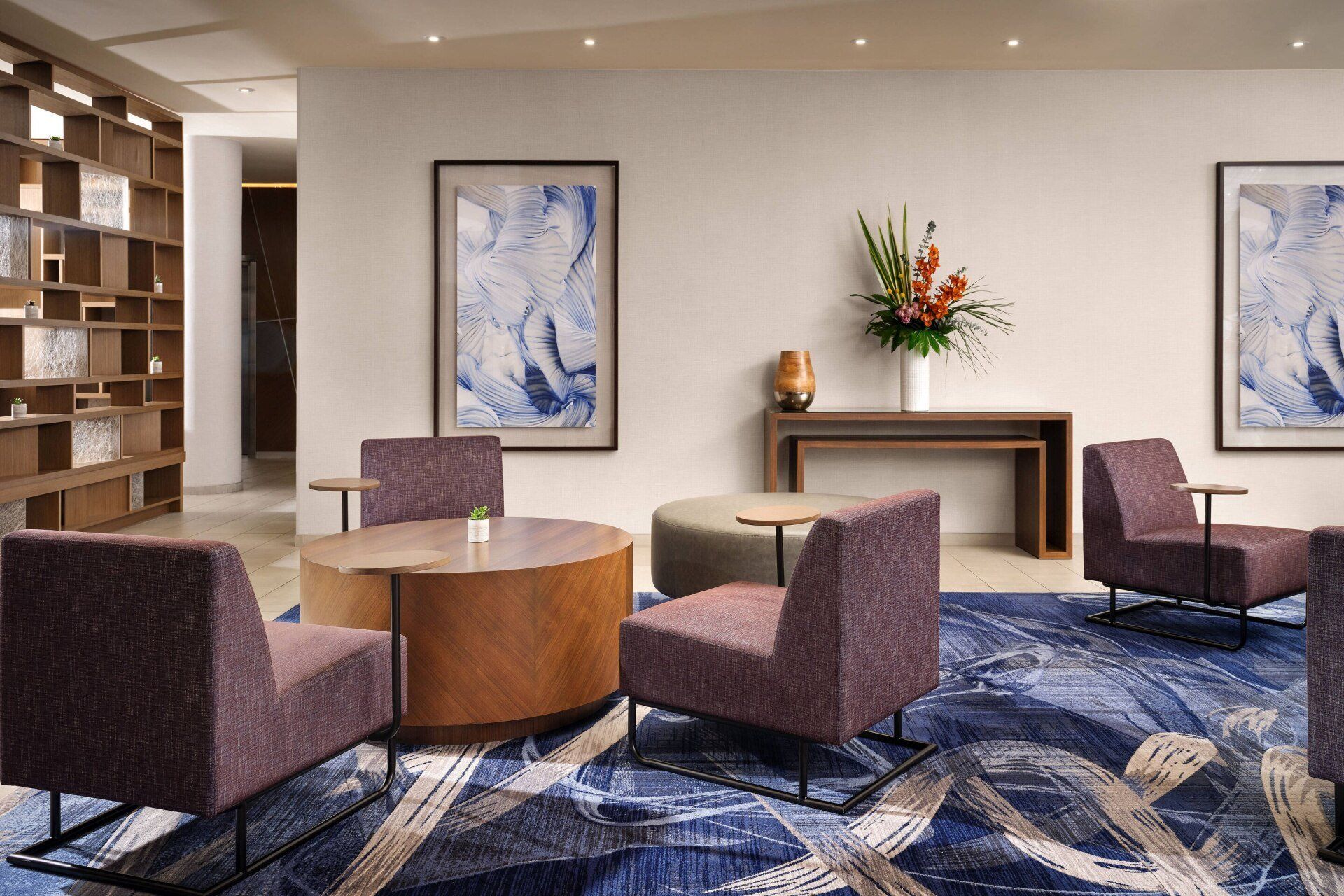 A living room with purple chairs , a table and a rug.