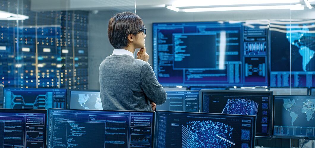 Person standing and looking at many computers