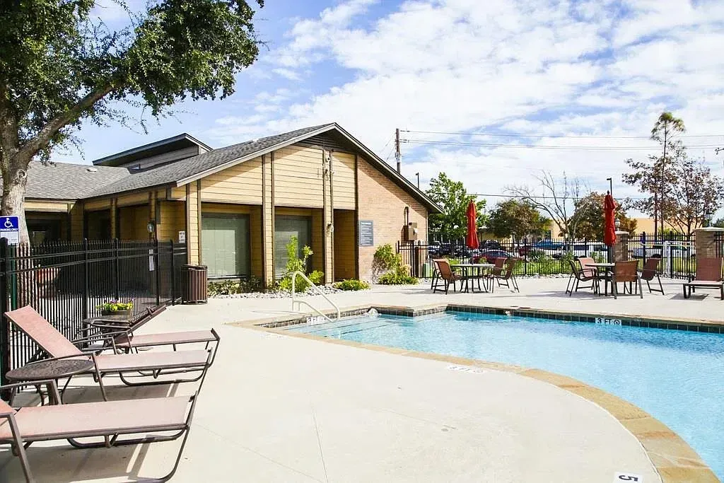 Swimming pool with lounge chairs and tables at a multifamily property.