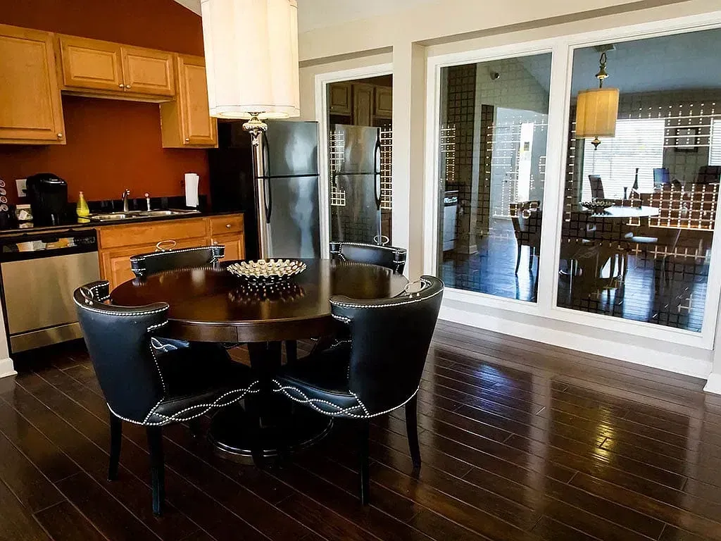 Dining area with round table and chairs, adjacent to kitchen.