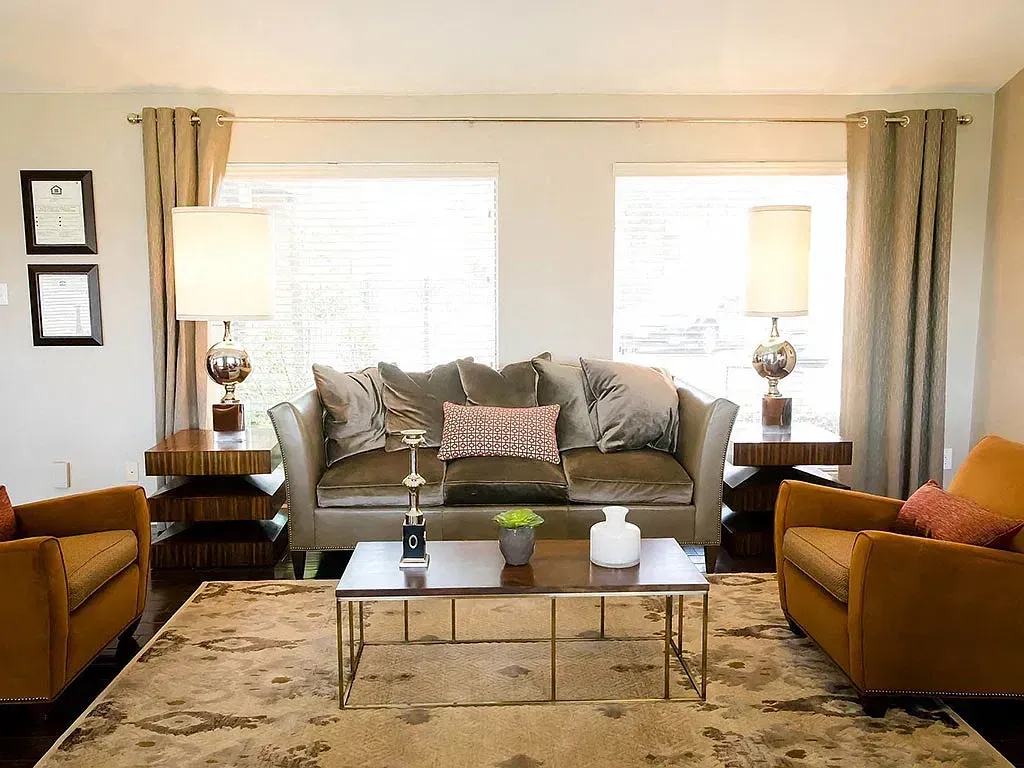 Modern living room with a sofa, two chairs, coffee table, and two lamps.