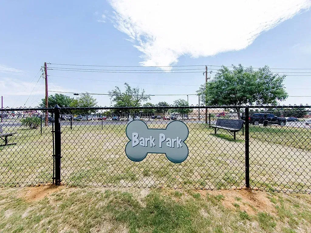 Dog park area with a 'Bark Park' sign and benches.
