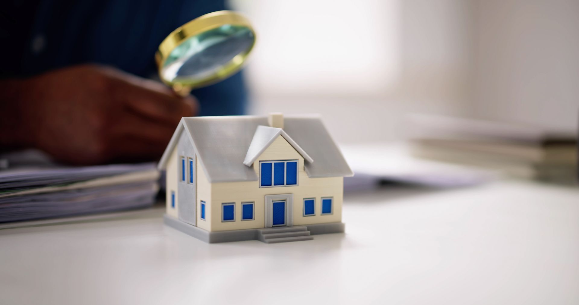 Man using magnifying glass behind a small house – Dayton, OH - C & G Mortgage Man using magnifying glass behind a small house – Dayton, OH - C & G Mortgage