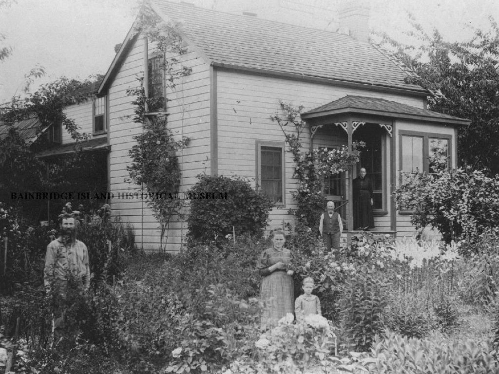 A black and white photo of a family in front of a house