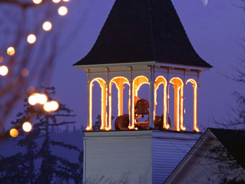 The bell tower of a church is lit up at night