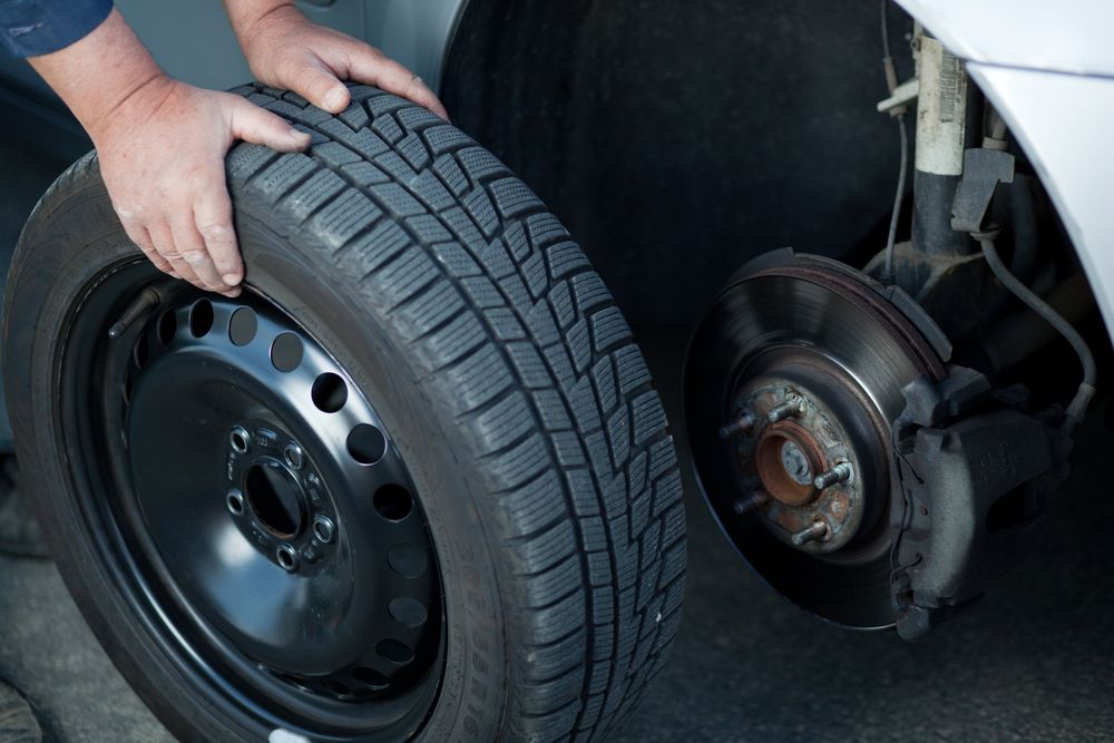 A Person is Changing a Tire on a Car — City Tyre Service in Darwin City, NT