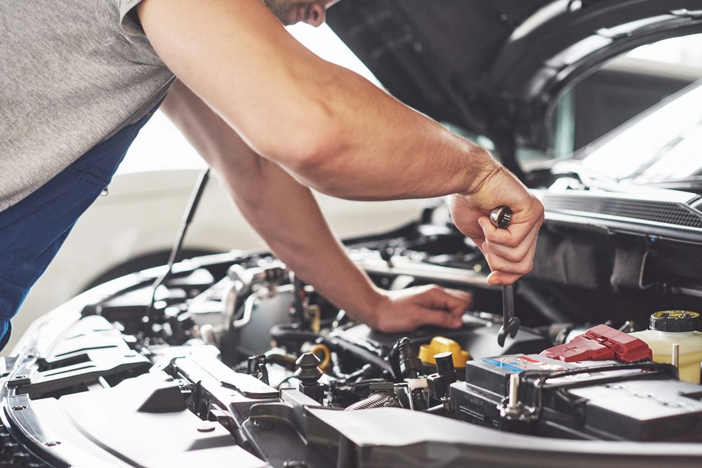 A Man is Working on the Engine of a Car With the Hood Open — City Tyre Service in Darwin City, NT