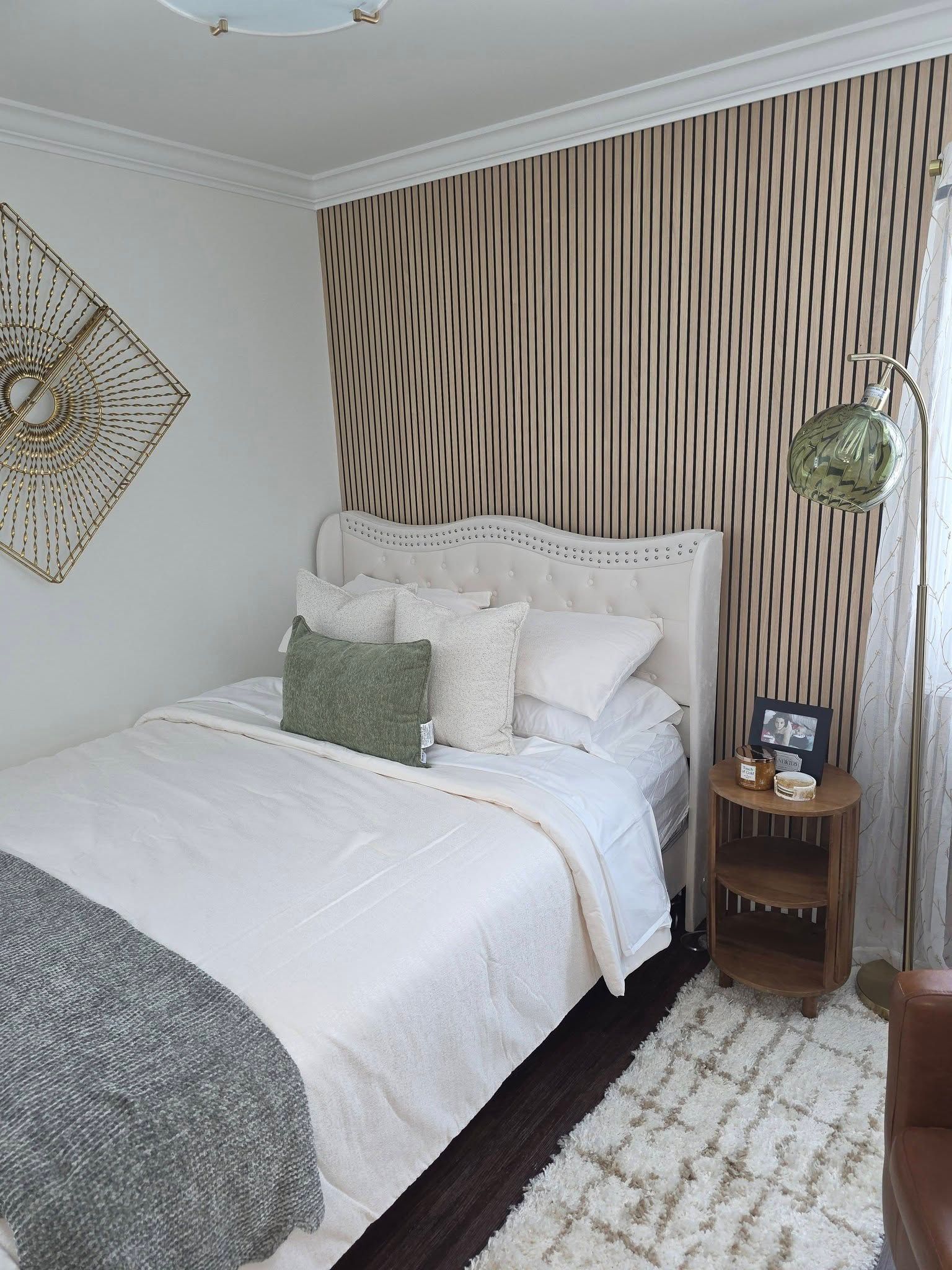 Cozy bedroom with a white bed, green accents, striped feature wall, and patterned rug