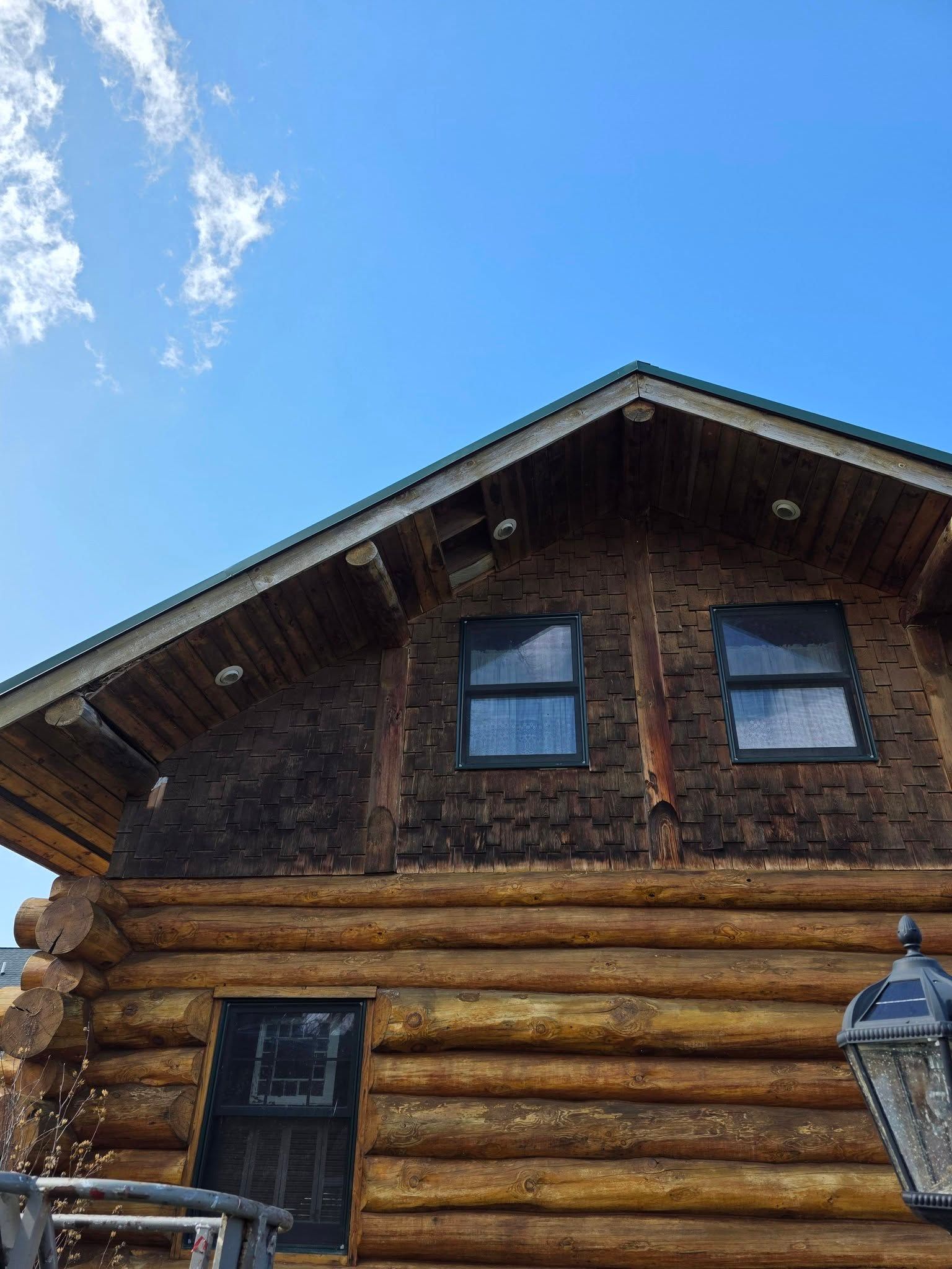 Wooden log cabin exterior with dark windows under a blue sky