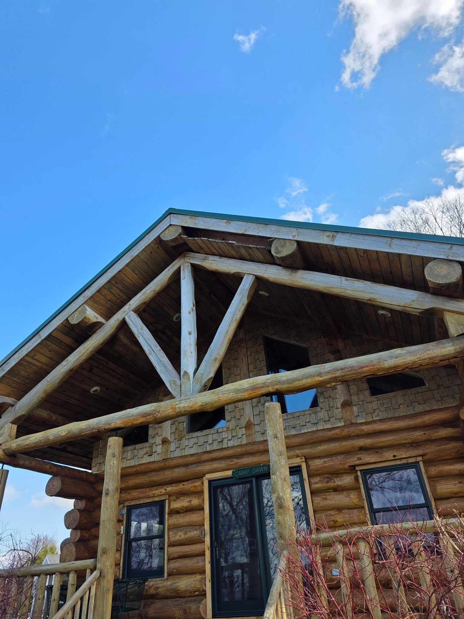Log cabin with rustic porch and white timber beams under a bright blue sky