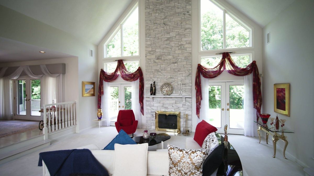 Living room with a tall stone fireplace and high windows at 14 Laureate Drive