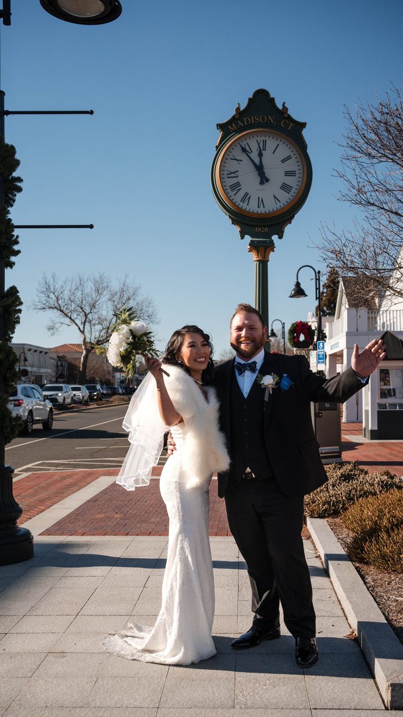 Amanda and Charles celebrate beneath a street clock marked Madison, CT