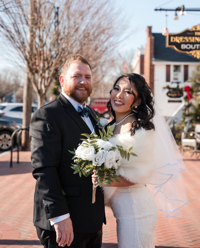 Amanda and Charles smile together on a sunny town sidewalk