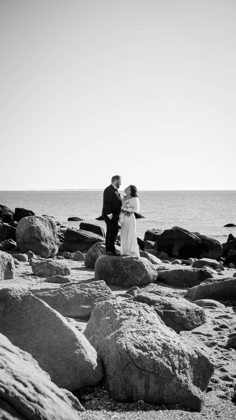 A black-and-white portrait places the couple among the shoreline rocks