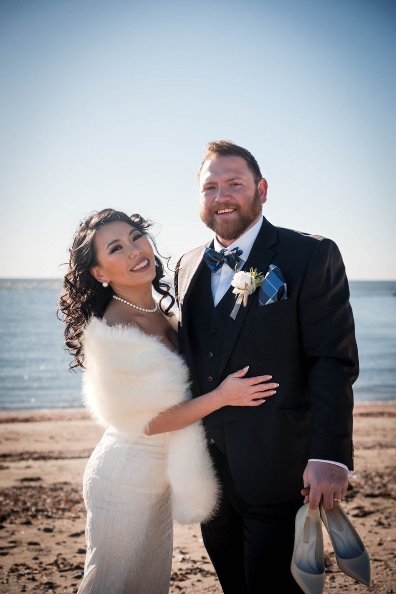Amanda and Charles laugh together with the water behind them