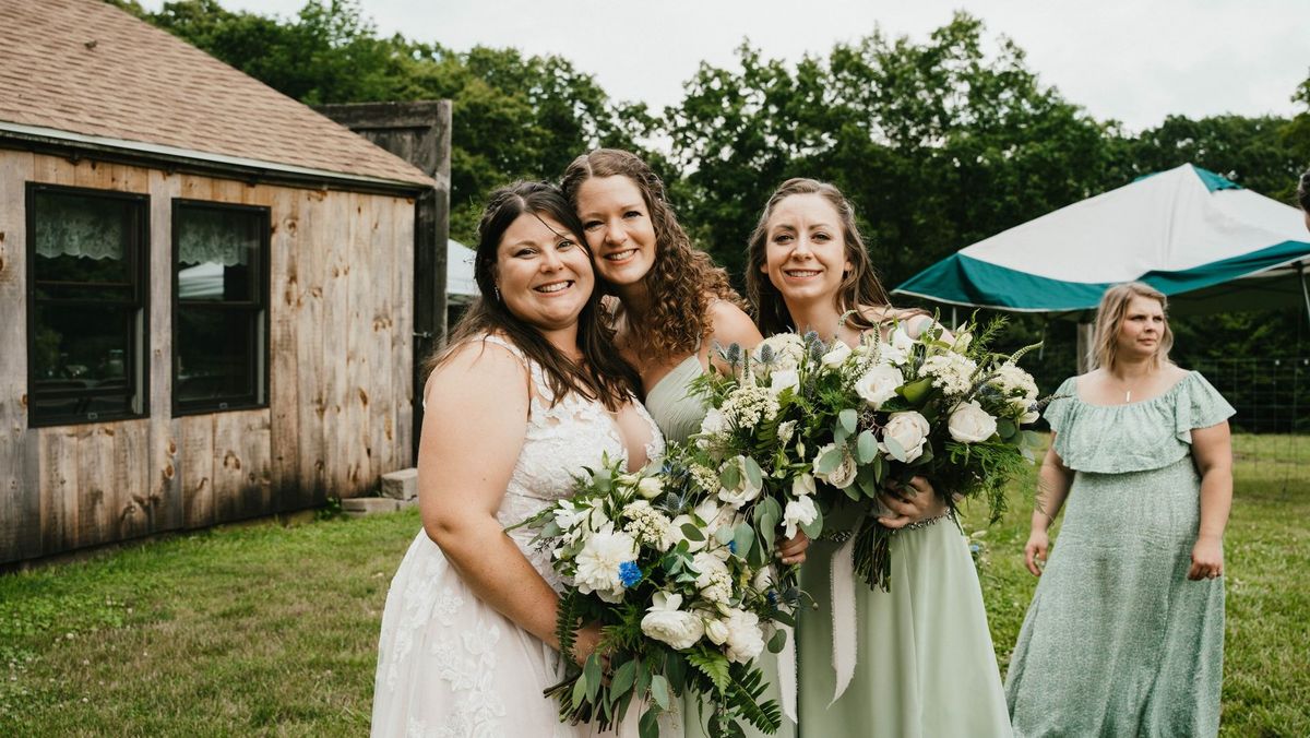 Ashley and members of her wedding party smile together with bouquets