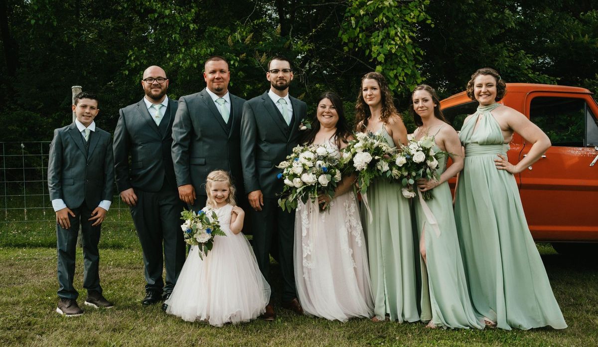 Ashley and Anthony pose with their wedding party beside the orange pickup truck