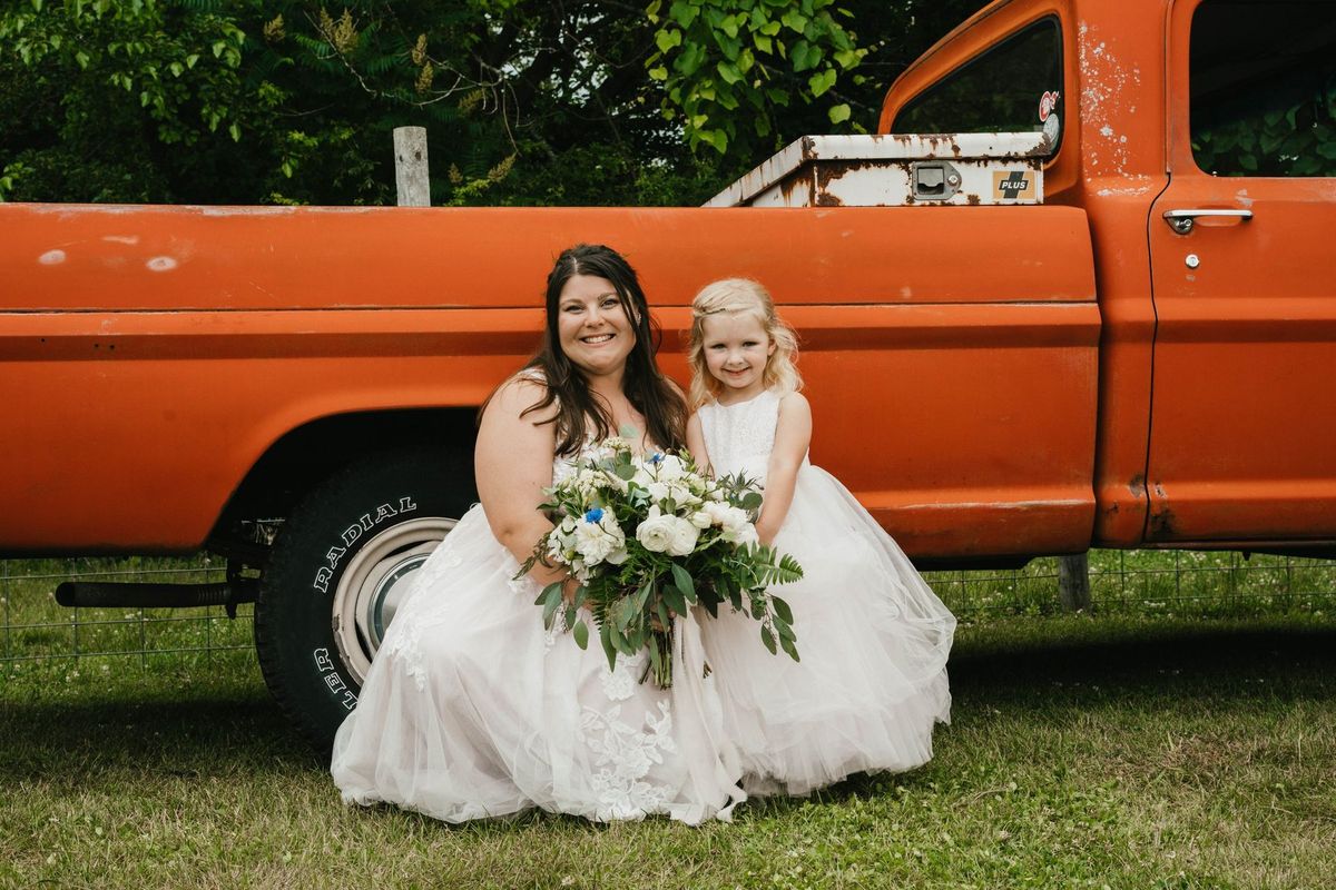 Ashley sits on the lawn with a child beside the orange truck