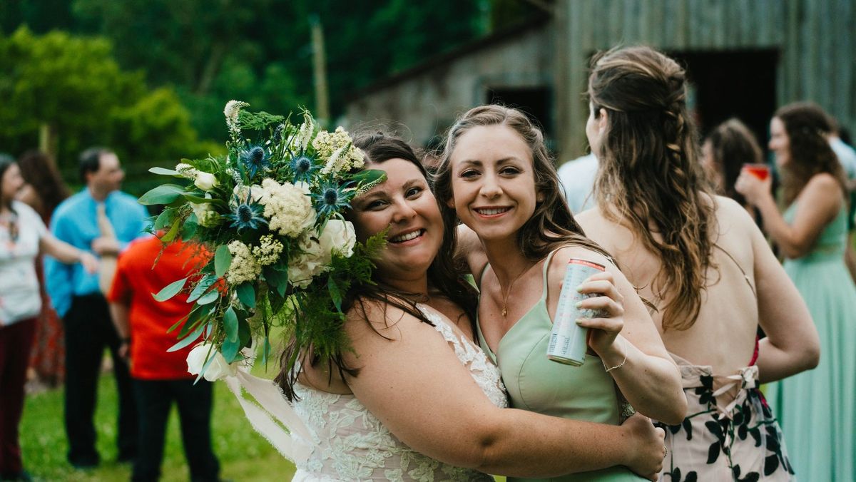 Ashley embraces a wedding party member while holding her bouquet
