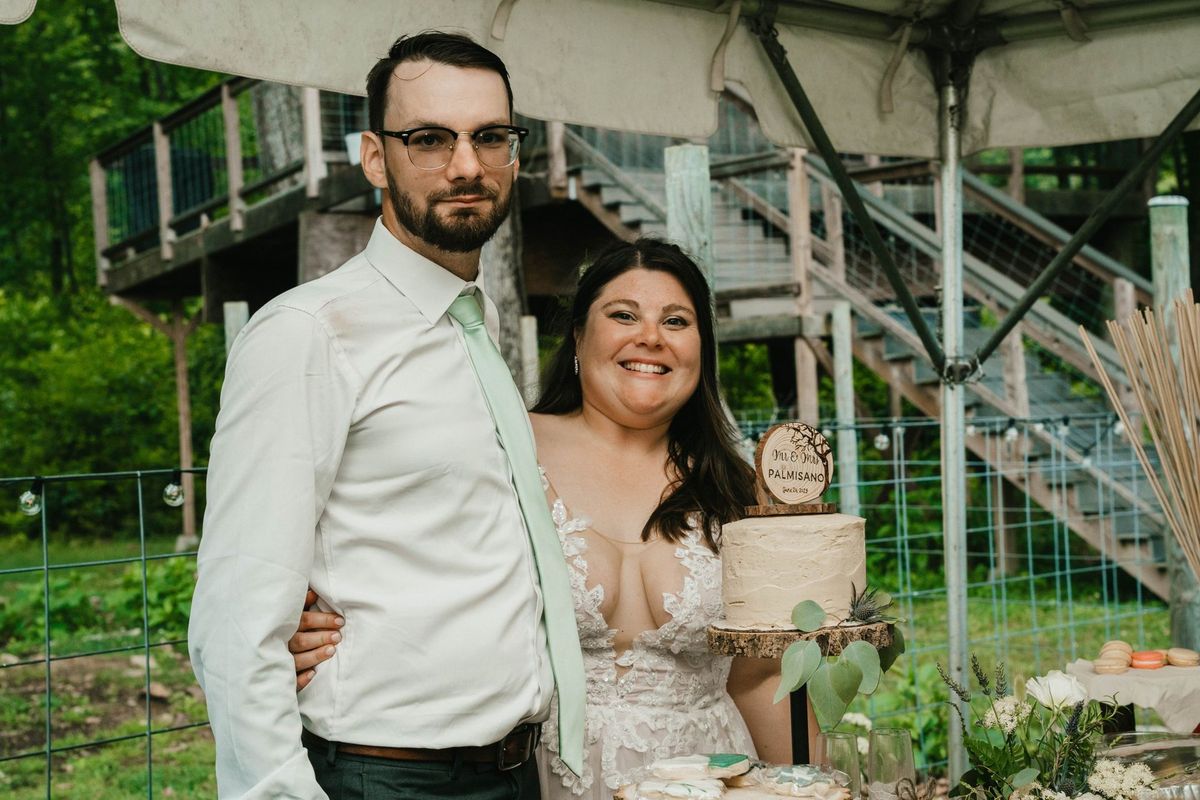 Ashley and Anthony stand beside their cake and dessert table