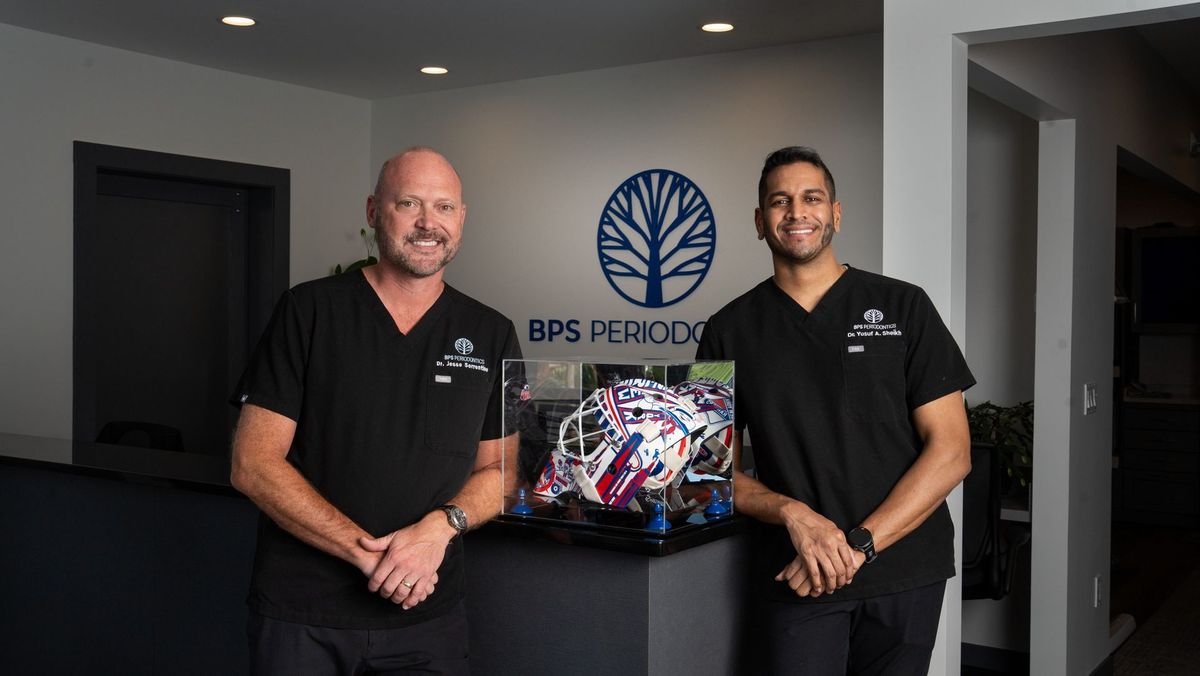 Two people at the branded reception desk of BPS Periodontics