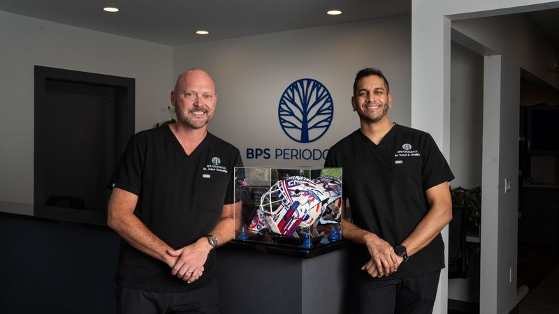 Two people at the branded reception desk of BPS Periodontics