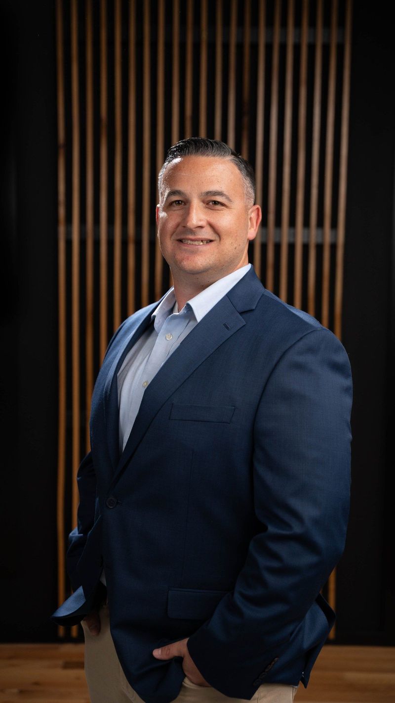 Brooke Team member in a blue suit smiling toward the camera