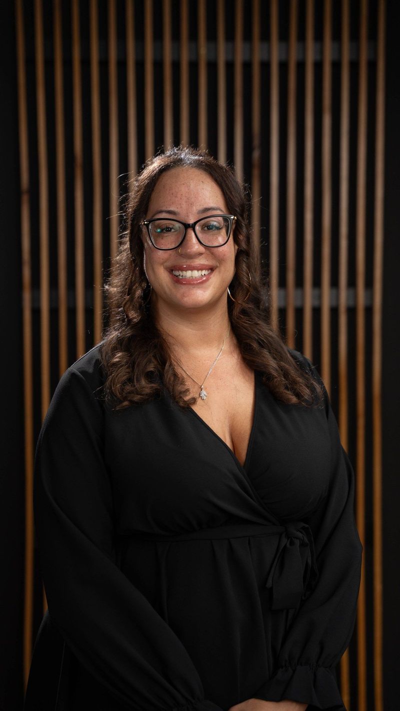 Brooke Team member with glasses in a black dress smiling toward the camera