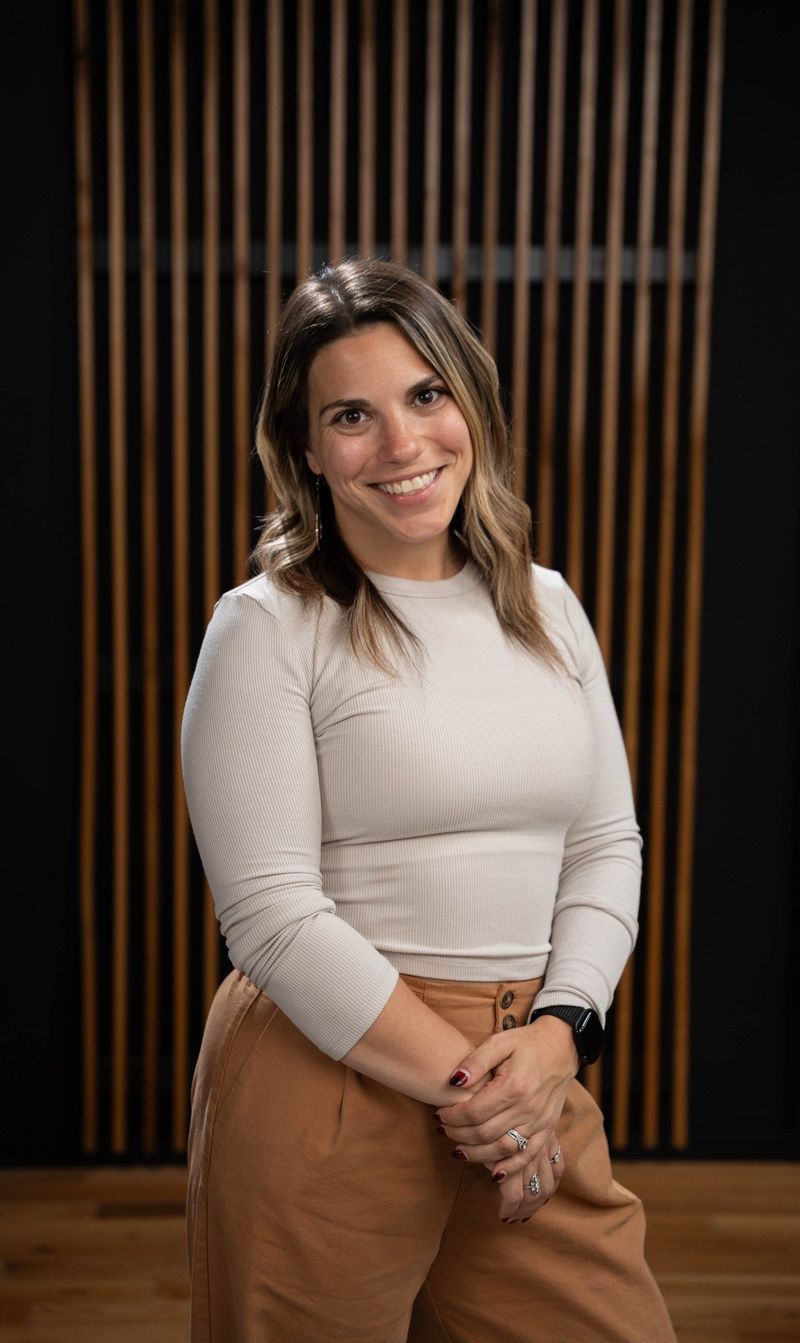 Brooke Team member in a cream top and brown trousers with hands together