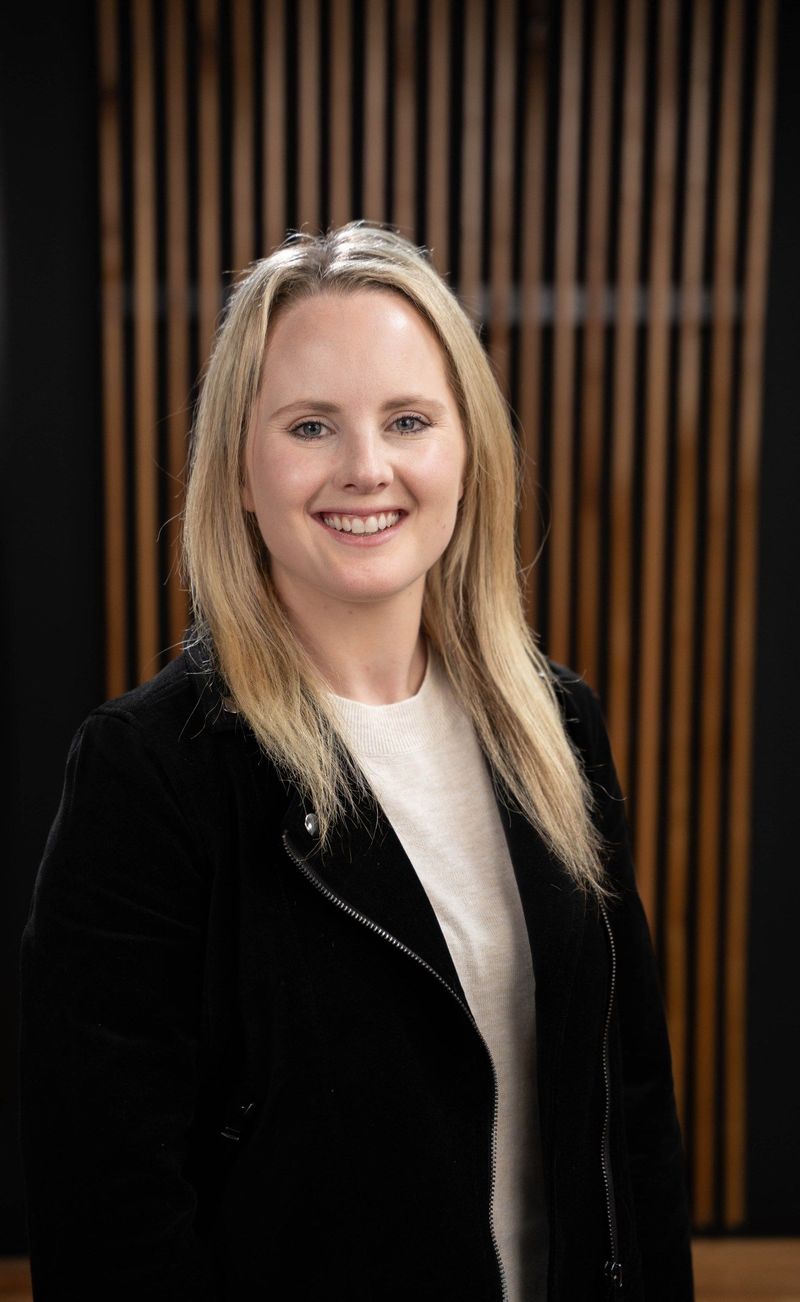 Brooke Team member in a black jacket and white blouse smiling toward the camera