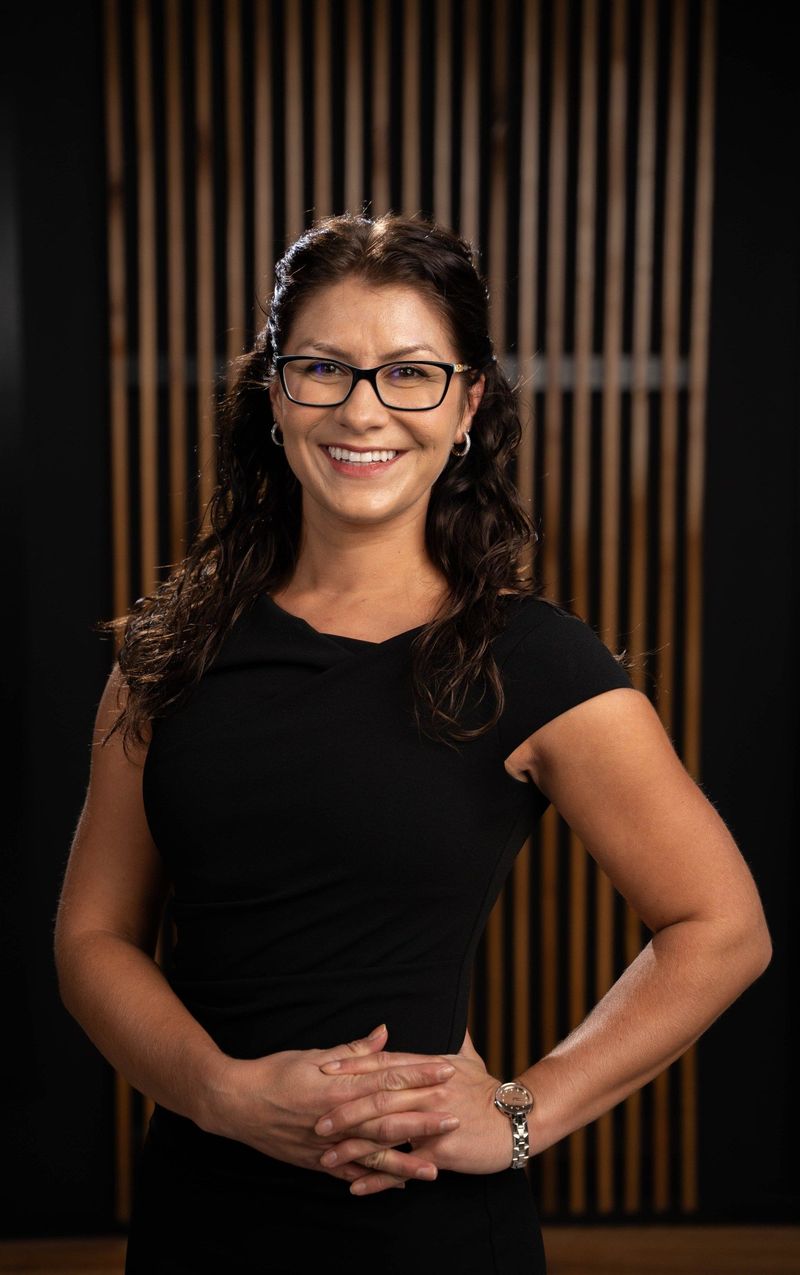 Brooke Team member in a black dress with hands together